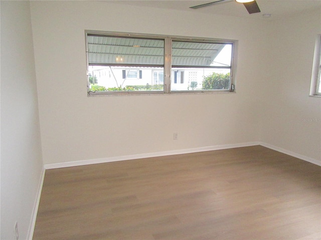 empty room with a healthy amount of sunlight, baseboards, and wood finished floors