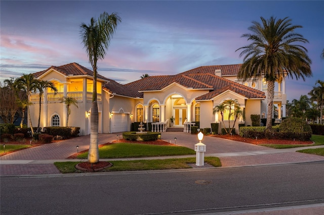 mediterranean / spanish house featuring a tiled roof, decorative driveway, french doors, and stucco siding