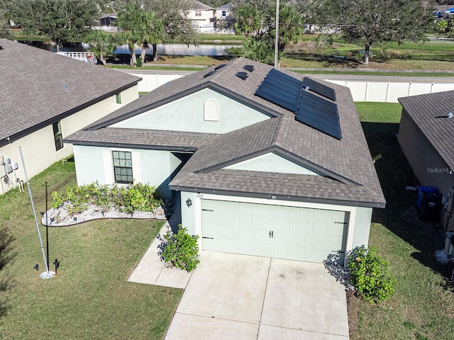 exterior space with stucco siding, concrete driveway, a front yard, and a shingled roof