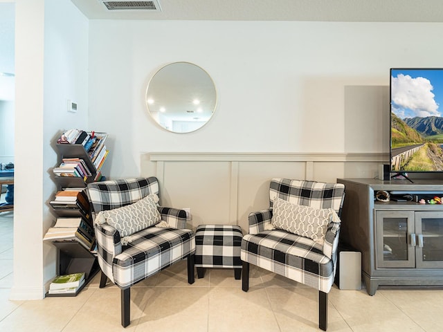 living area with tile patterned floors, visible vents, and wainscoting