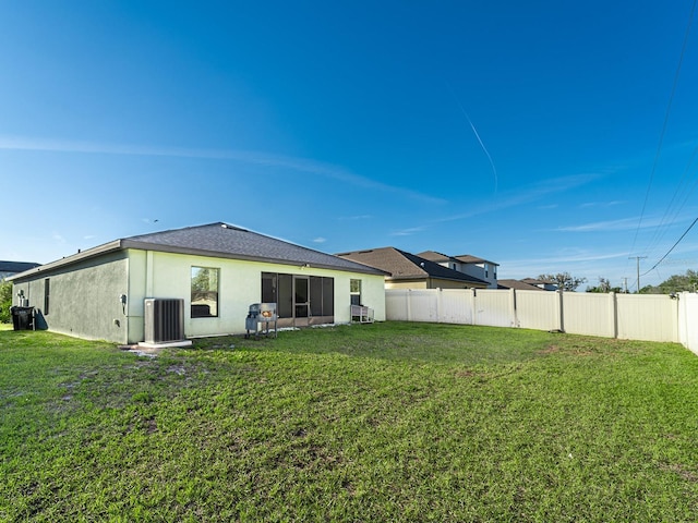 back of house with stucco siding, a yard, cooling unit, and fence