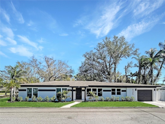 view of front facade with stucco siding, driveway, an attached garage, and a front lawn