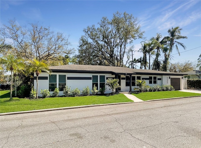 view of front of property featuring stucco siding, an attached garage, and a front lawn