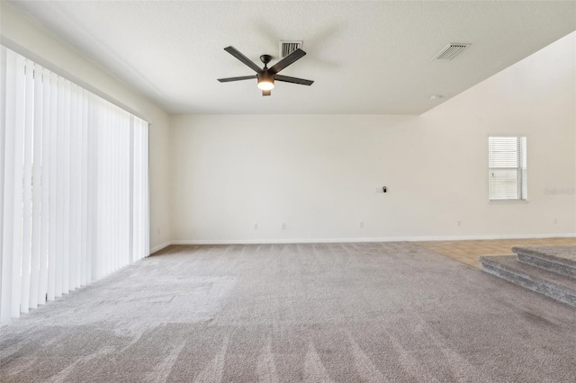 carpeted empty room with a ceiling fan, visible vents, and baseboards