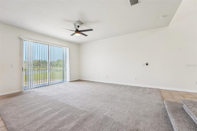 unfurnished room featuring visible vents, light tile patterned flooring, ceiling fan, a textured ceiling, and light carpet