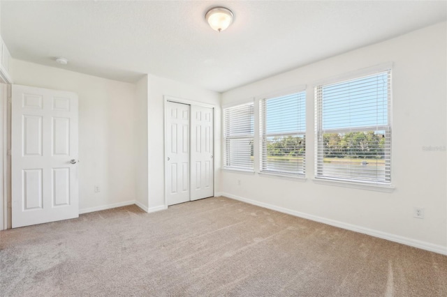 unfurnished bedroom with a closet, baseboards, and carpet floors