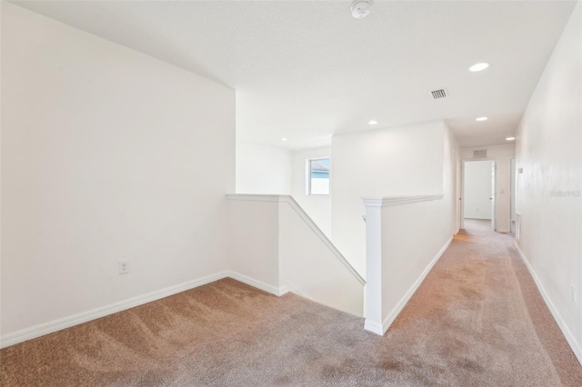 hall featuring baseboards, visible vents, recessed lighting, light carpet, and an upstairs landing