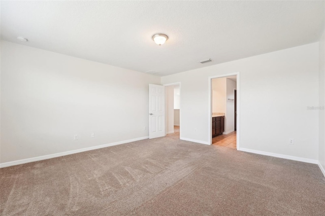 empty room featuring visible vents, baseboards, and light colored carpet