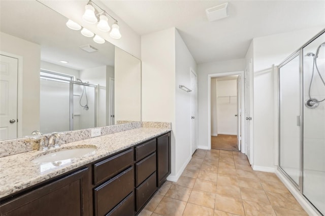 bathroom featuring a spacious closet, visible vents, baseboards, a stall shower, and vanity