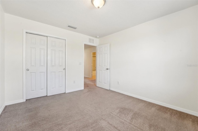 unfurnished bedroom featuring a closet, baseboards, carpet, and visible vents