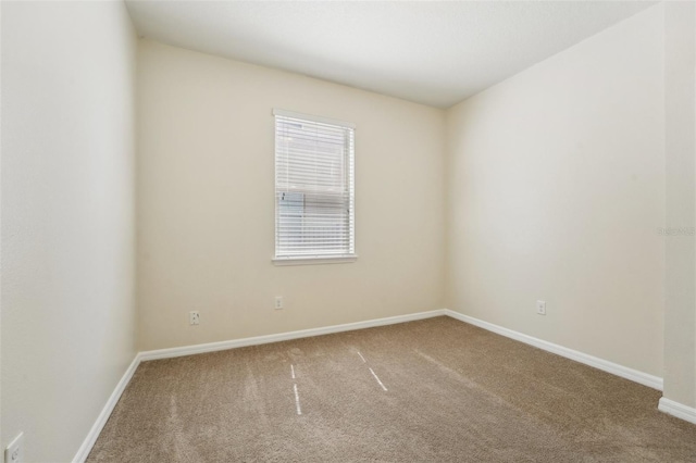 carpeted spare room featuring baseboards