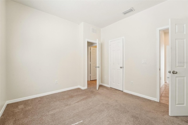 unfurnished bedroom with light carpet, visible vents, and baseboards