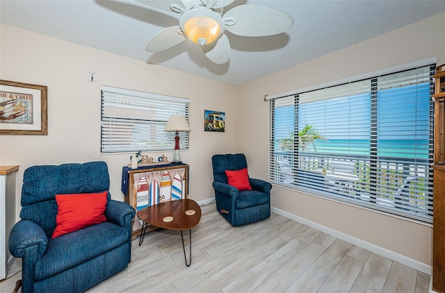 living area with a ceiling fan, baseboards, and light wood finished floors