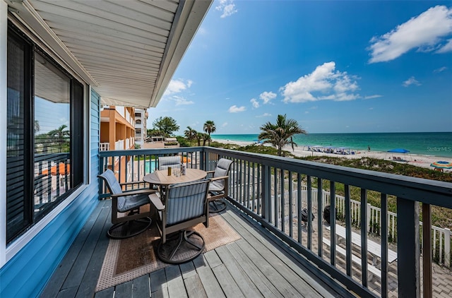 balcony with outdoor dining space, a water view, and a view of the beach