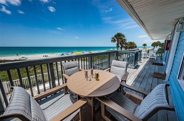 deck with a water view, outdoor dining area, and a view of the beach