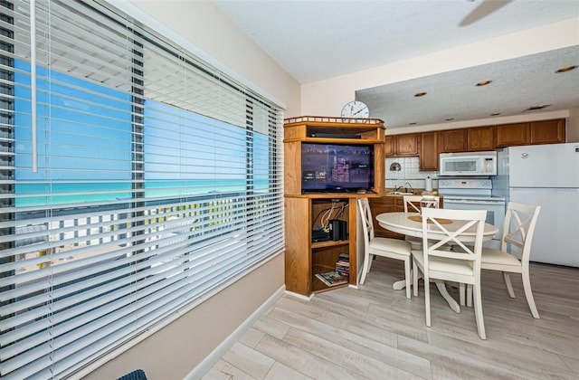 dining area featuring baseboards, light wood-style flooring, and a textured ceiling