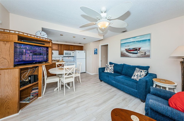 living area with light wood-type flooring, visible vents, ceiling fan, and a textured ceiling