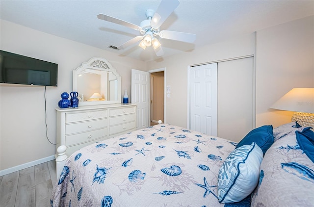 bedroom featuring baseboards, visible vents, a ceiling fan, wood finished floors, and a closet