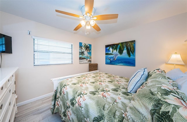 bedroom with a ceiling fan, light wood-style flooring, and baseboards