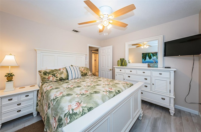 bedroom with ceiling fan, wood finished floors, visible vents, and baseboards