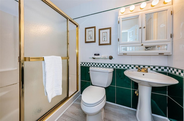 full bathroom with toilet, a sink, tile walls, decorative backsplash, and a stall shower