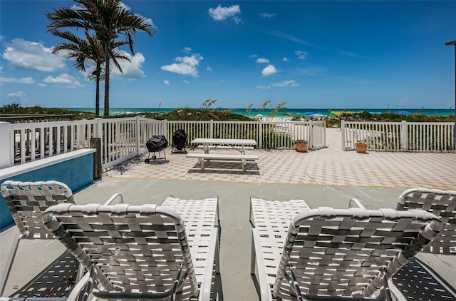 view of patio featuring a water view, a view of the beach, and outdoor dining space