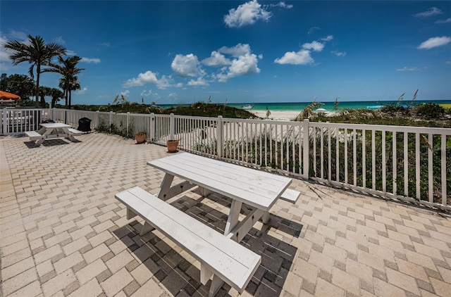 view of patio / terrace featuring a beach view, outdoor dining space, and a water view