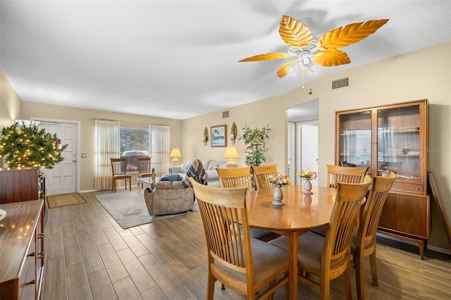 dining area with a ceiling fan, baseboards, visible vents, and wood finished floors