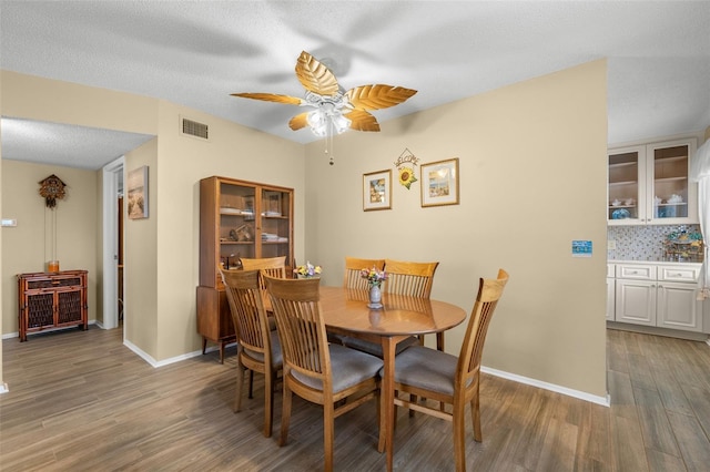 dining area with ceiling fan, a textured ceiling, light wood-style flooring, visible vents, and baseboards