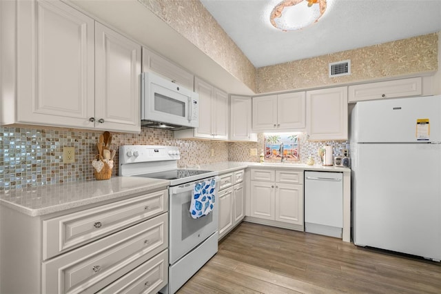 kitchen with white appliances, light wood-style flooring, visible vents, and white cabinets