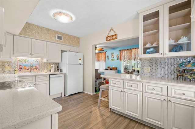 kitchen with backsplash, glass insert cabinets, white cabinets, light wood-type flooring, and white appliances