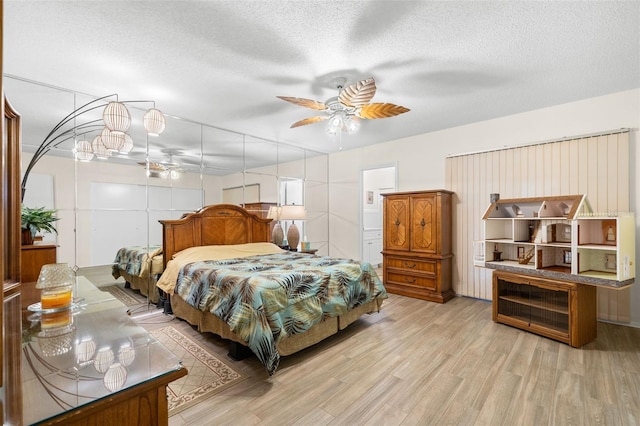 bedroom with a ceiling fan, light wood-type flooring, and a textured ceiling