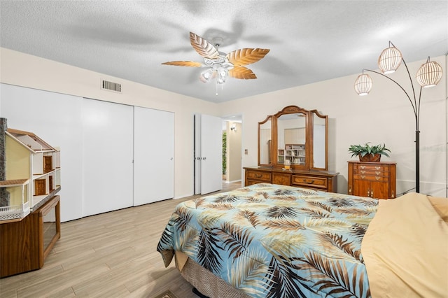 bedroom with a textured ceiling, light wood finished floors, a closet, and visible vents