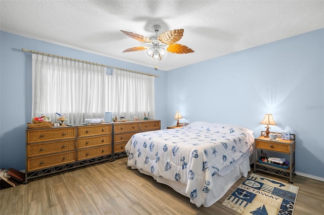 bedroom featuring a textured ceiling, wood finished floors, and a ceiling fan