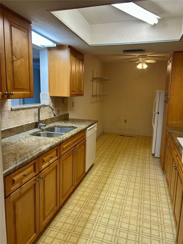 kitchen featuring white appliances, brown cabinetry, and a sink