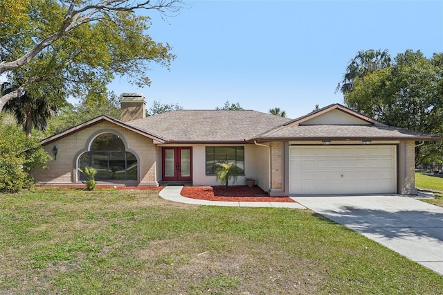 view of front facade with an attached garage, french doors, brick siding, and driveway