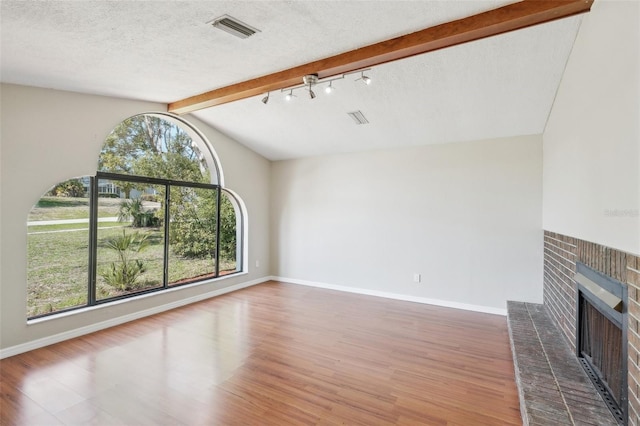 unfurnished living room featuring visible vents, a brick fireplace, baseboards, wood finished floors, and a textured ceiling