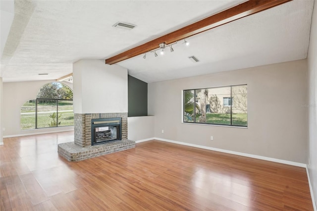 unfurnished living room featuring lofted ceiling with beams, baseboards, and light wood-style flooring