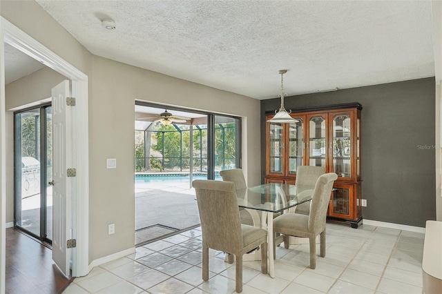 dining area featuring a wealth of natural light, ceiling fan, a textured ceiling, and baseboards