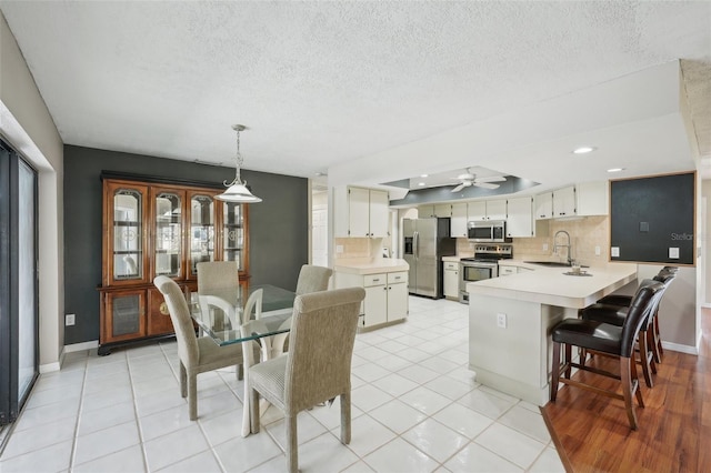 dining area with light tile patterned floors, baseboards, a textured ceiling, and ceiling fan