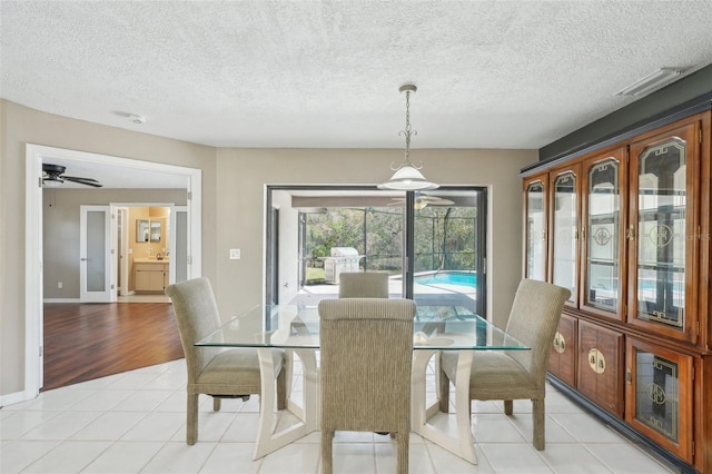 dining room featuring light tile patterned floors, baseboards, a textured ceiling, and ceiling fan