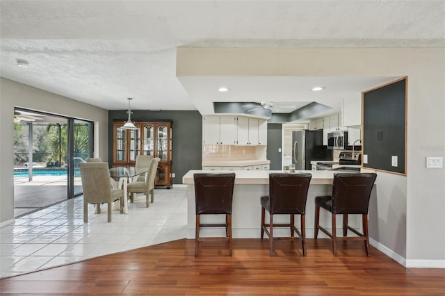 kitchen with light wood finished floors, ceiling fan, light countertops, appliances with stainless steel finishes, and a peninsula