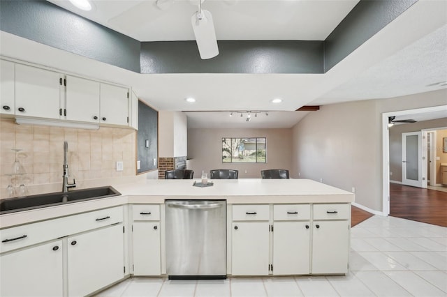 kitchen with tasteful backsplash, dishwasher, light countertops, a peninsula, and a sink