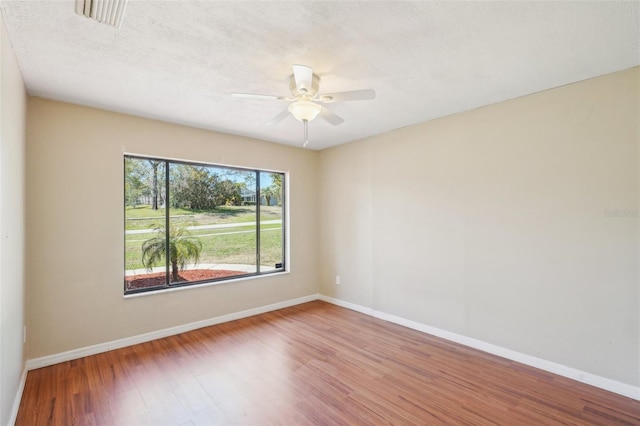 spare room with ceiling fan, baseboards, a textured ceiling, and wood finished floors