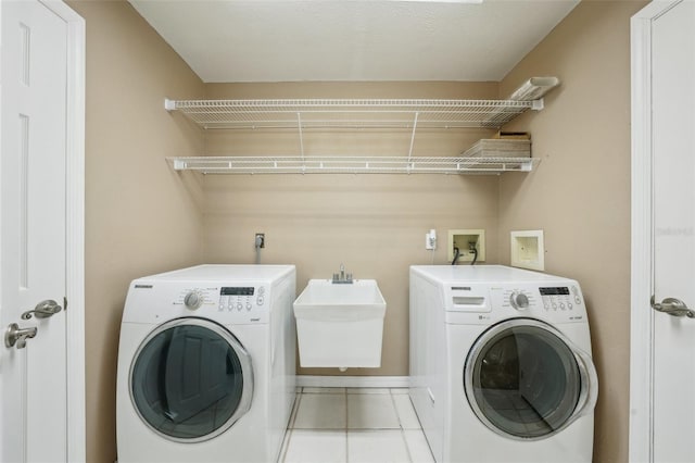 laundry room with laundry area, light tile patterned flooring, baseboards, and washer and clothes dryer