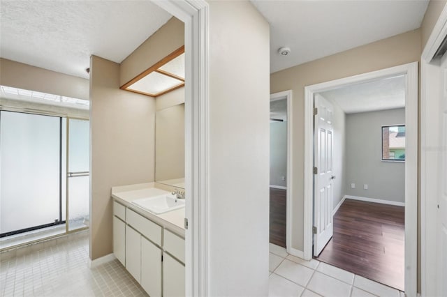 bathroom featuring tile patterned flooring, a textured ceiling, vanity, and baseboards