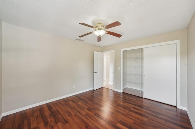 unfurnished bedroom featuring visible vents, wood finished floors, a closet, baseboards, and ceiling fan