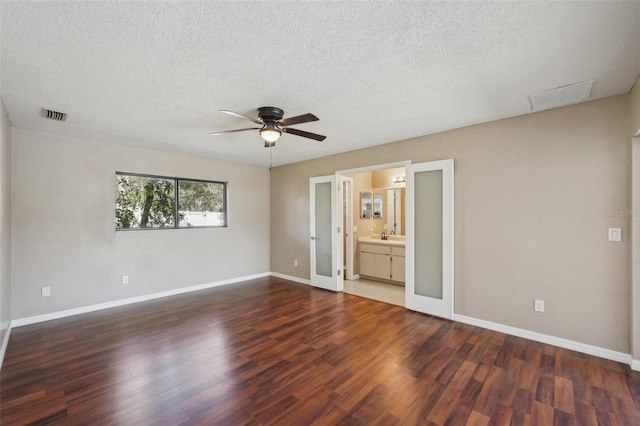 unfurnished bedroom with visible vents, a textured ceiling, wood finished floors, baseboards, and ceiling fan