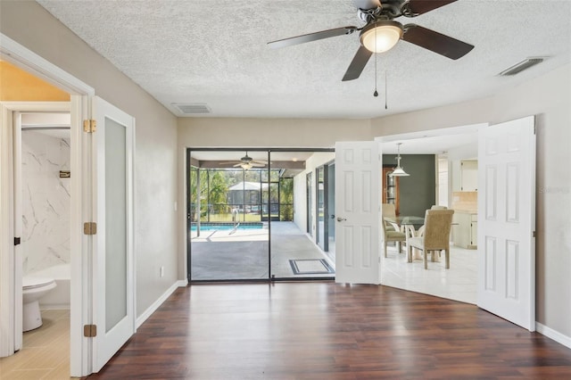 unfurnished room with visible vents, wood finished floors, and ceiling fan