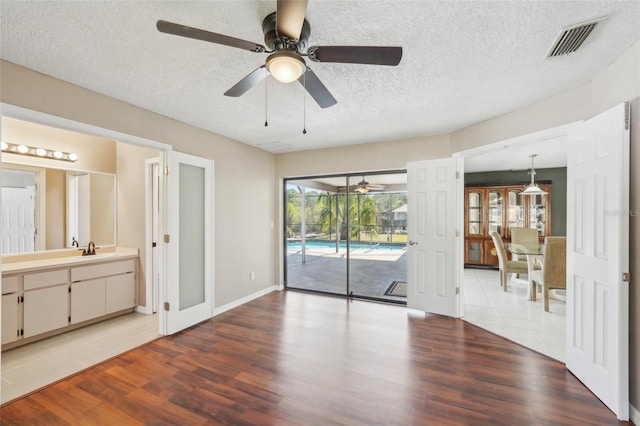 interior space featuring visible vents, light wood-style floors, a textured ceiling, a ceiling fan, and a sink